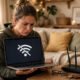 Person with a laptop showing disconnected WiFi, with a home router nearby